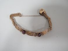 AN ANTIQUE ROLLED GOLD BRACELET SET WITH PURPLE STONES