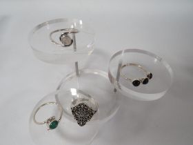 THREE DECORATIVE SILVER DRESS RINGS TOGETHER WITH AN UNMARKED EXAMPLE (4)