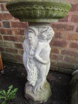 A CONCRETE BIRD BATH DEPICTING THREE LADIES