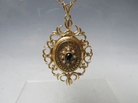 A HALLMARKED 9CT GOLD LOCKET, with fancy openwork border, set with a central cabochon garnet, with a