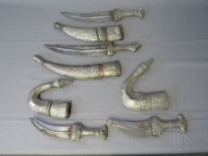 FOUR MIDDLE EASTERN JAMBIYA DAGGERS, all with typical curved blades and sheet white metal