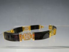 AN ORIENTAL YELLOW METAL AND ONYX PANEL LINK BRACELET, marked to clasp 14K, HKong with hallmarks