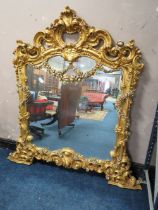 A LARGE MODERN GILT COMPOSITE OVERMANTLE MIRROR, with Rococo and floral scrolling, 172 x 170 cm