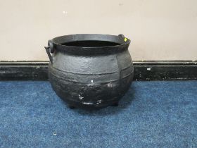 A LARGE AND HEAVY CAST CAULDRON, with swing handle, on three feet, H 38 cm, W 49 cm A/FCondition