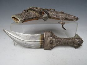 A VINTAGE MIDDLE EASTERN JAMBYA DAGGER, with white metal handled accoutrements and leather covered