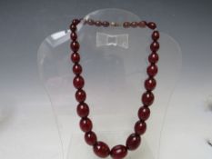 A VINTAGE SINGLE STRAND CHERRY AMBER GRADUATED BEAD NECKLACE, largest bead Dia. approx. 2.2 cm,