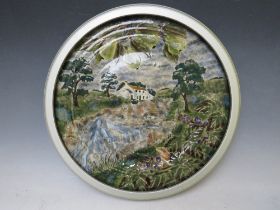 A LARGE COBRIDGE CIRCULAR CHARGER BY ANJI DAVENPORT, decorated with a country house by a stream,