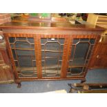 A 20TH CENTURY MAHOGANY GLAZED THREE DOOR BOOKCASE ON BALL AND CLAW FEET 126 X 145 CM