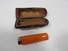 A CASED AMBER CHEROOT HOLDER WITH HALLMARKED 9 CARAT GOLD BAND