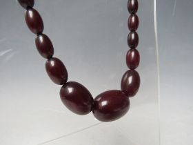 A CHERRY RED FATURAN AMBER GRADUATED OVAL BEAD NECKLACE, approx L 54 cm, approx weight 39 g
