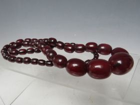 A CHERRY RED FATURAN AMBER GRADUATED OVAL BEAD NECKLACE, approx L 68 cm, approx weight 63 g