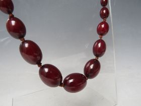 A CHERRY RED FATURAN AMBER GRADUATED OVAL BEAD NECKLACE, approx L 70 cm, approx weight 51 g