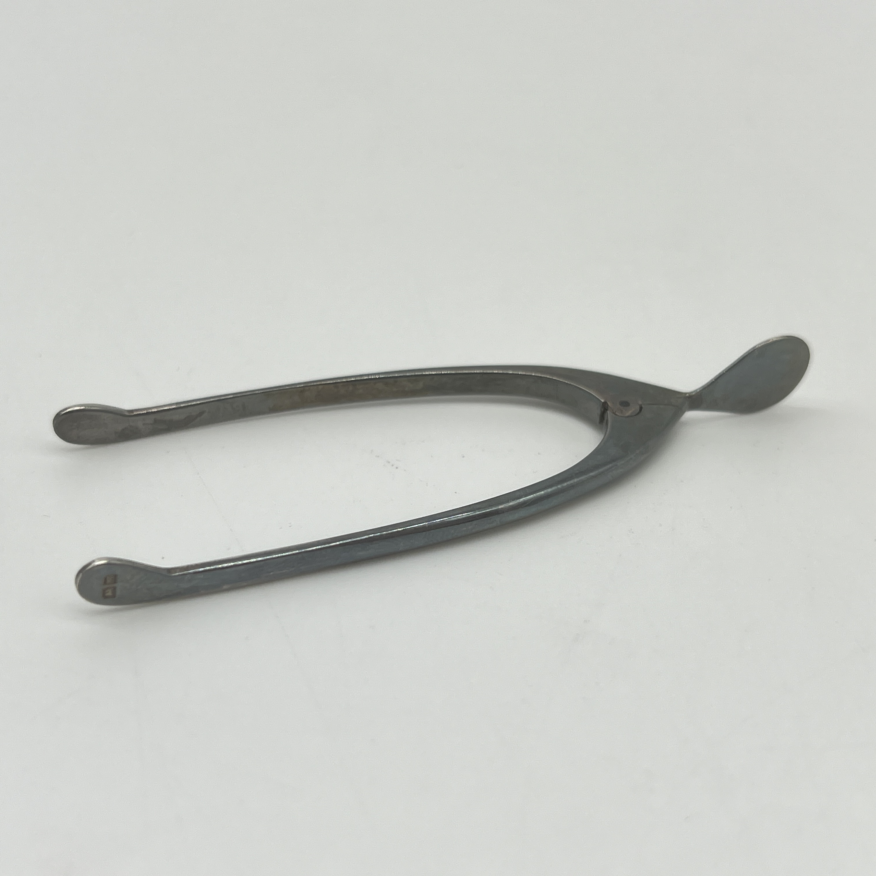 A set of silver wishbone hinged sugar tongs