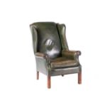 A George III-style wingback fireside chair with close nailed aged bottle green hide stuff over