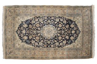 A blue/ black ground Nain rug with a central boss with a field of leaves and flowers within borders.