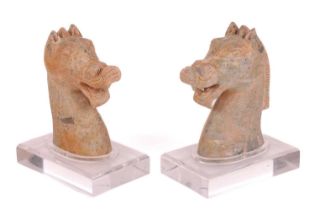 A similar near pair of Chinese weathered green carved Jade figures of horse heads, possibly Han