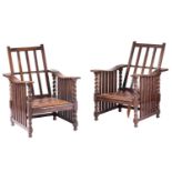 A pair of early twentieth-century reclining oak armchairs in the manner of Jas Shoolbred stood on