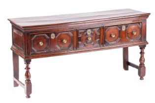 A Charles II oak three-drawer dresser base with a planked top and geometrically moulded drawer