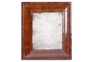 A late seventeenth-century walnut and olive wood cushion frame mirror, with a subtle old degraded