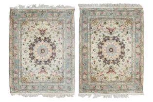 A pair of Ivory ground Tabriz rugs with central boss with Perian blue and claret detail within a