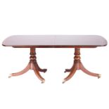 A George III style mahogany and crossbanded extending dining table on twin pedestal base twentieth