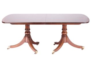 A George III style mahogany and crossbanded extending dining table on twin pedestal base twentieth