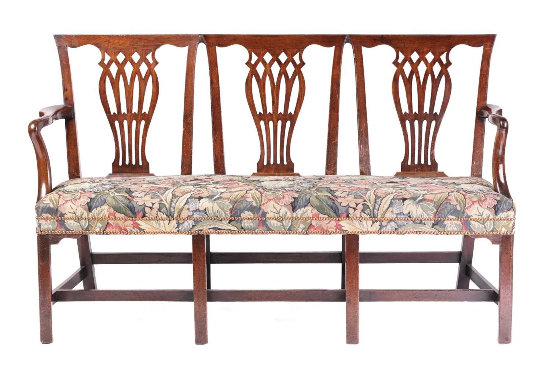 A George III mahogany triple chair back hall seat, with angular backs above three bullrush and