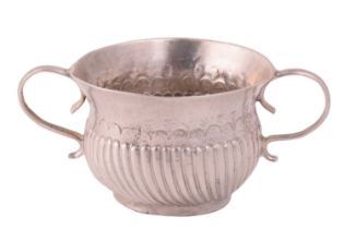 A Queen Anne miniature silver porringer with flared rim, gadrooned lower body and scrolling handles,