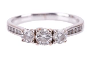 A diamond three-stone ring. Set with round brilliant-cut diamonds, the principal diamond measures