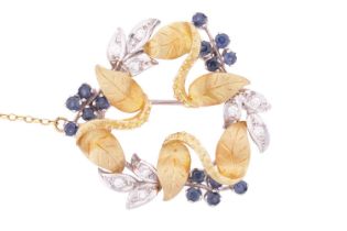 A sapphire and diamond floral brooch designed as a wreath of foliage and berries, in white and