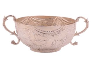 A 17th-century style white metal porringer, the flat chased decoration in the form of stylised