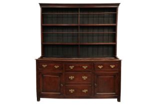 A George III oak cupboard dresser and Delft rack, the base with a central bank of drawers flanked by
