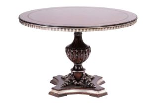 A contemporary circular dining table with swag decoration and silvered detail, raised on a single