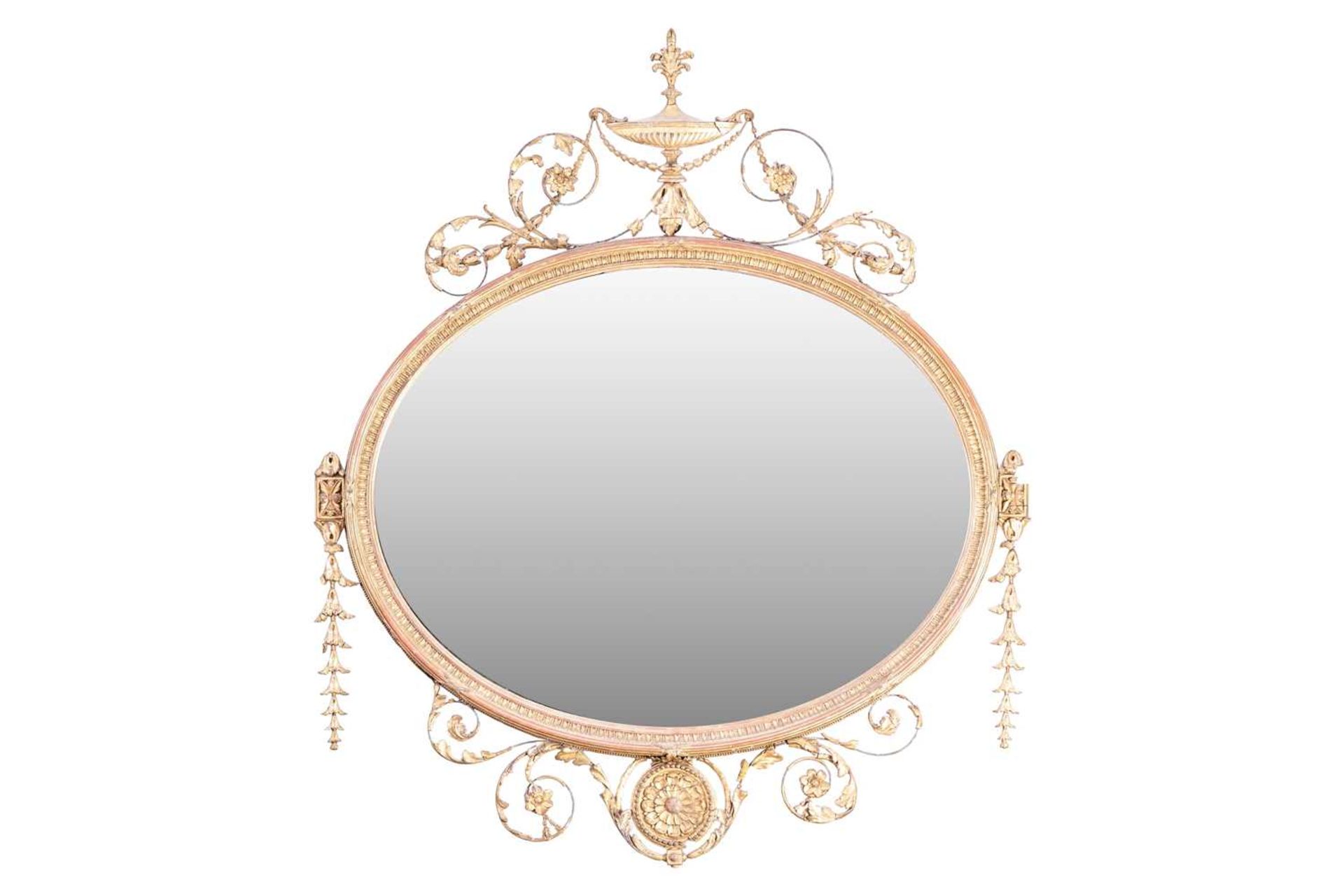 An Edwardian carved and gilt gesso oval overmantel mirror with urn surmount and swag decoration. 109