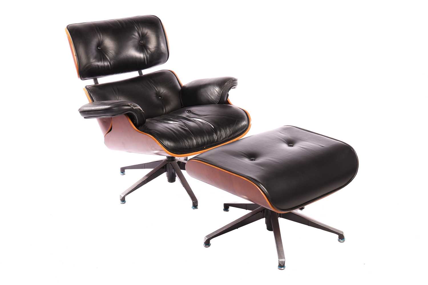 A reproduction Eames-style lounge chair and ottoman with black hide upholstery, in need of attention