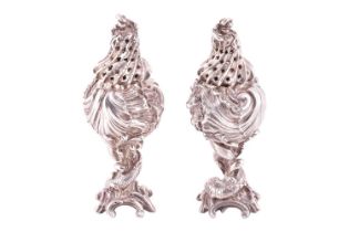 A pair of Continental heavy-cast silver "Rocaile" peppers of pedestal form, bearing one