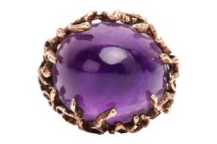 A Modernist amethyst cocktail ring, featuring a large and high-domed amethyst of 19.8 x 17.3 x 13.