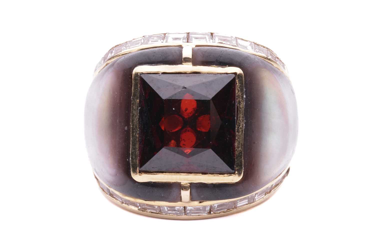 A gem-set cocktail ring, centred with a square scissors-cut garnet in collet, shoulders inlaid with 