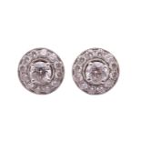 A pair of diamond stud earrings with diamond-set enhancer halos, each central round brilliant diamon