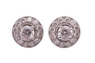 A pair of diamond stud earrings with diamond-set enhancer halos, each central round brilliant