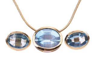 A Swiss blue topaz pendant and earring suite, each oval gemstone bezel-set in yellow mounts tested
