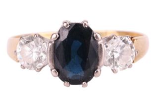 A sapphire and diamond three-stone ring, centred with an oval-cut sapphire in dark greenish-blue