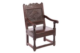 An oak wainscot armchair, 17th century and later, with carved decoration, the arms terminating in