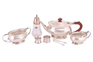 A three-piece silver tea set, oval with husk borders and leaf-capped scroll handles, on oval skirt f