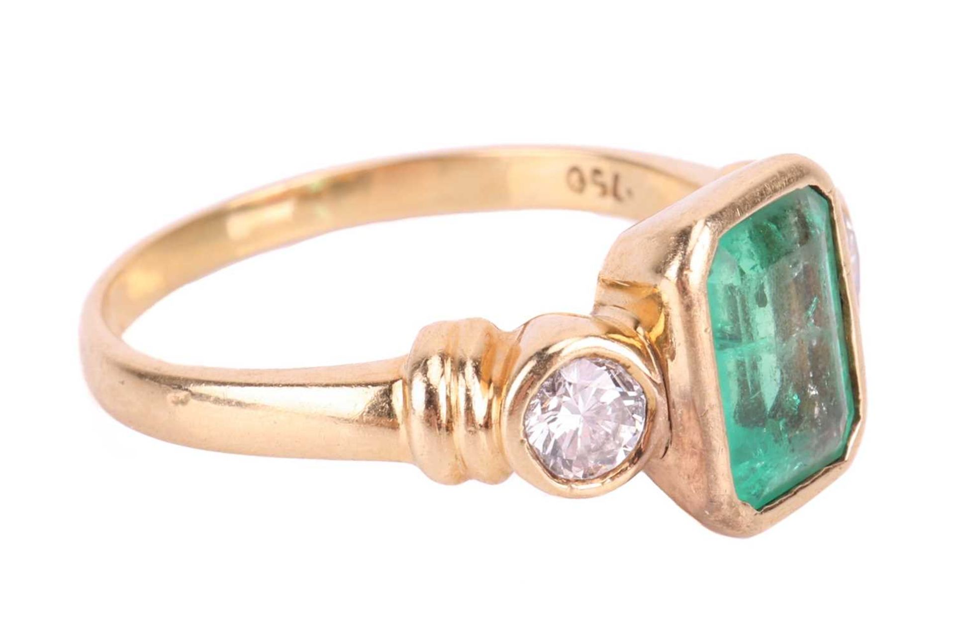 An emerald and diamond three stone ring, set with an emerald measuring 8 x 6 x 3.6mm, flanked by rou - Image 2 of 4