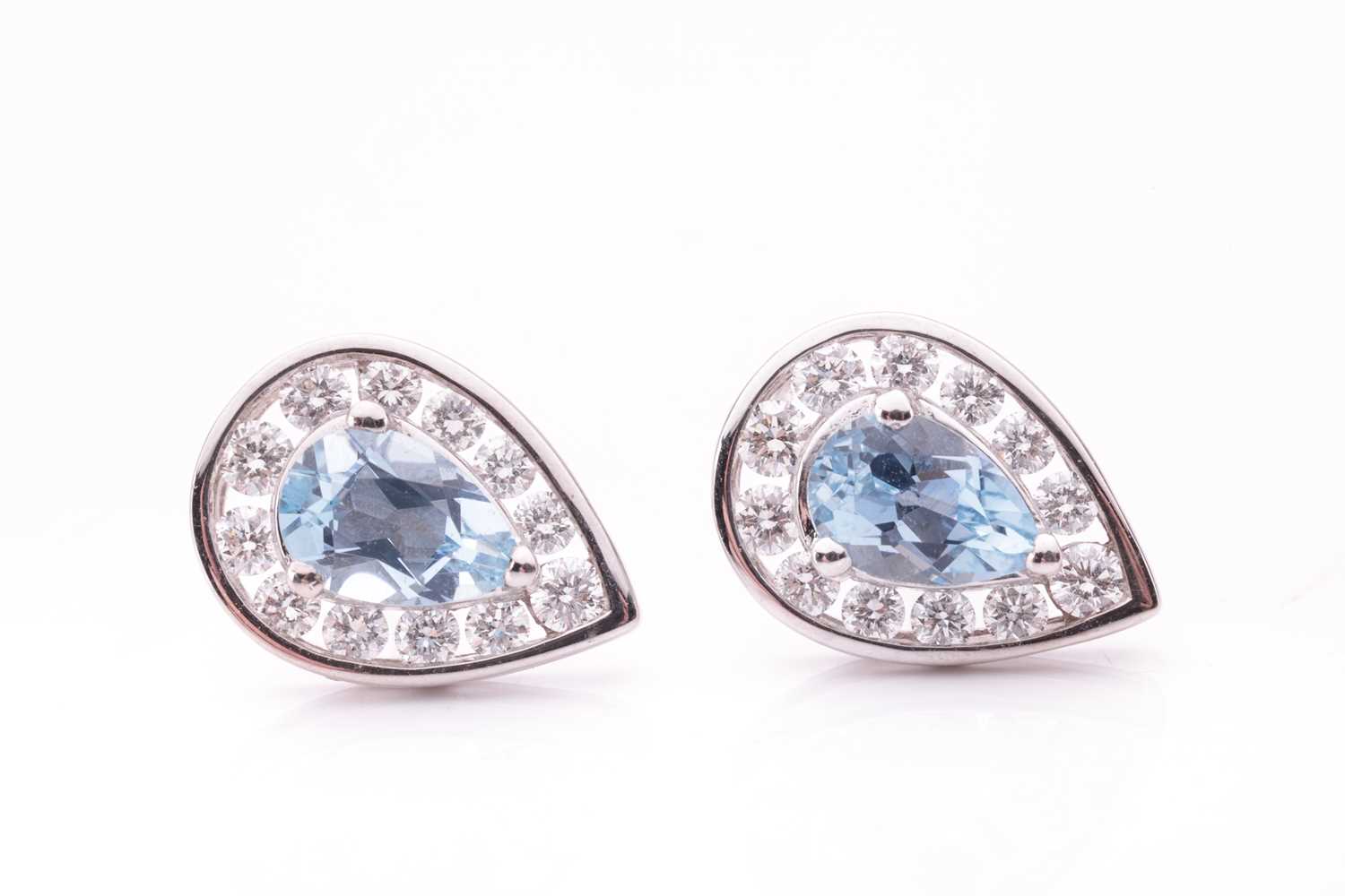 A pair of aquamarine and diamond stud earrings, each featuring a pear cut aquamarine with an estimat