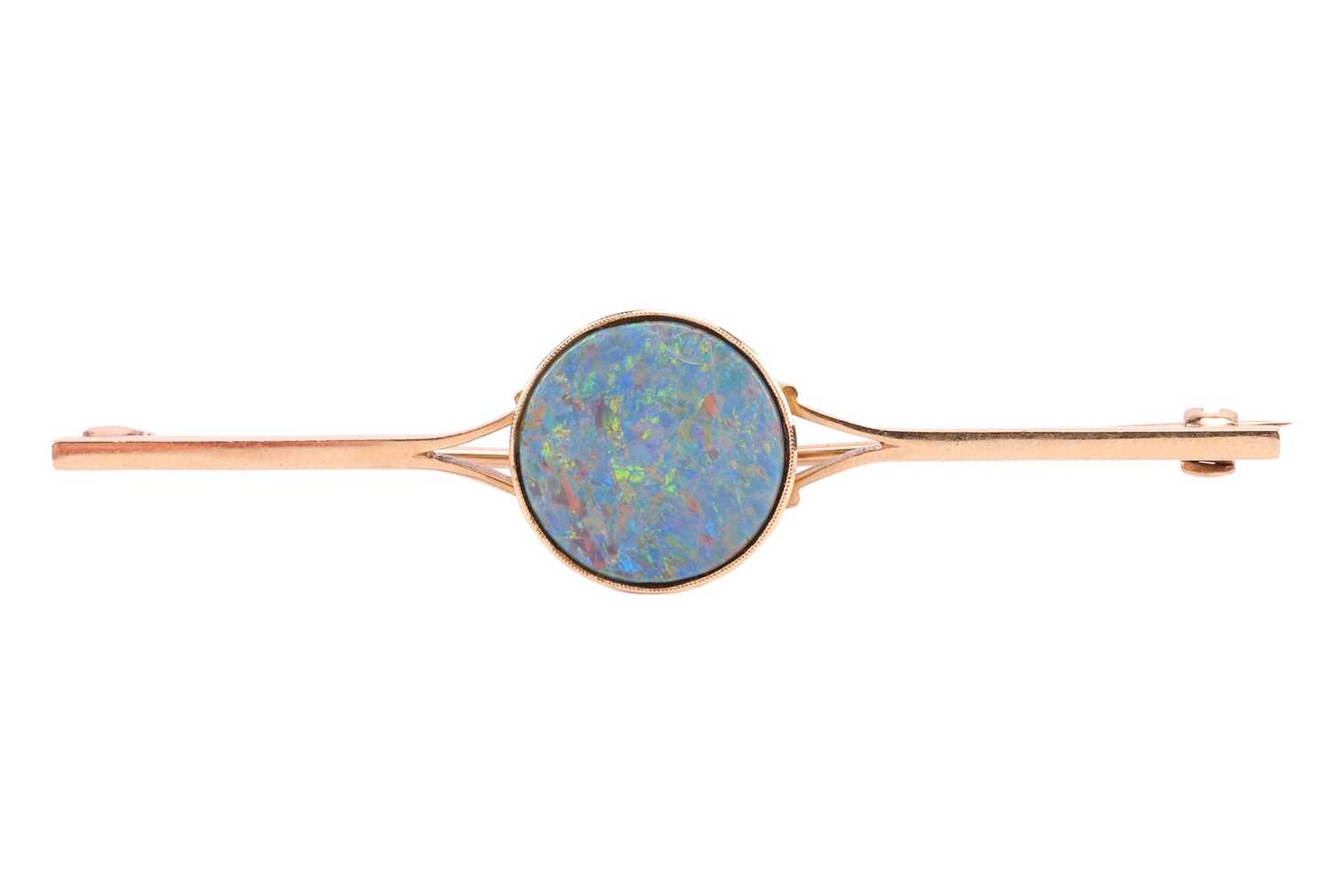 A bar brooch set with a round opal doublet, approximately measures 14.0 mm across, displaying strong