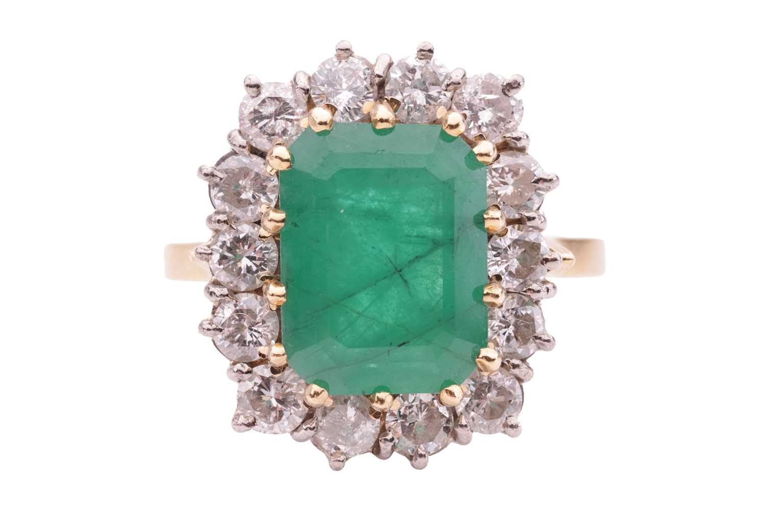 An emerald and diamond cluster ring, set with an emerald measuring 10.8 x 8.2 x 5.2mm, encircled by 