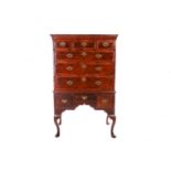 A George II walnut chest on stand, with diagonal crossbanding, the cavetto moulded cornice over thre