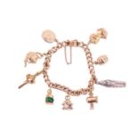 A charm bracelet featuring nine charms including examples of an Egyptian mummy charm, a 9ct gold tea